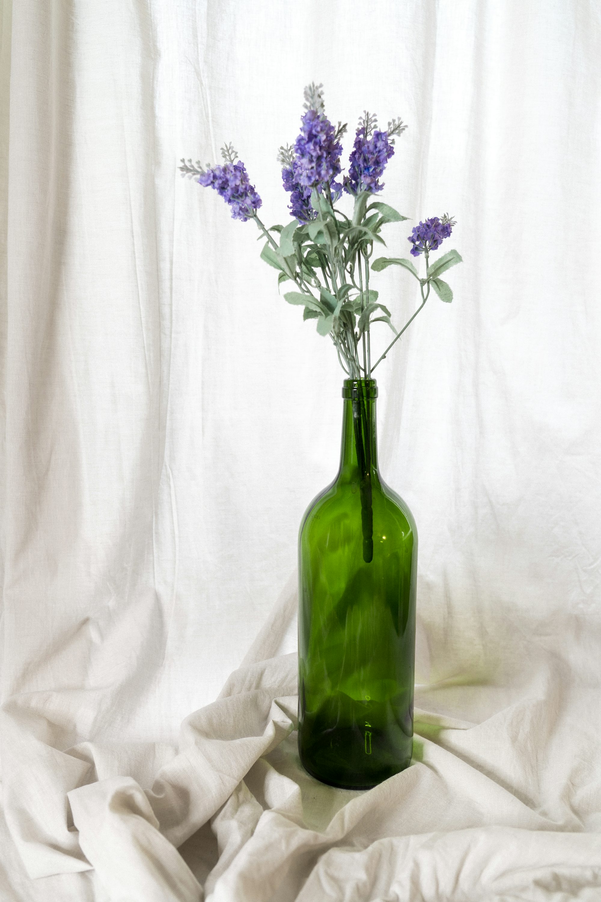 a green bottle with some purple flowers in it