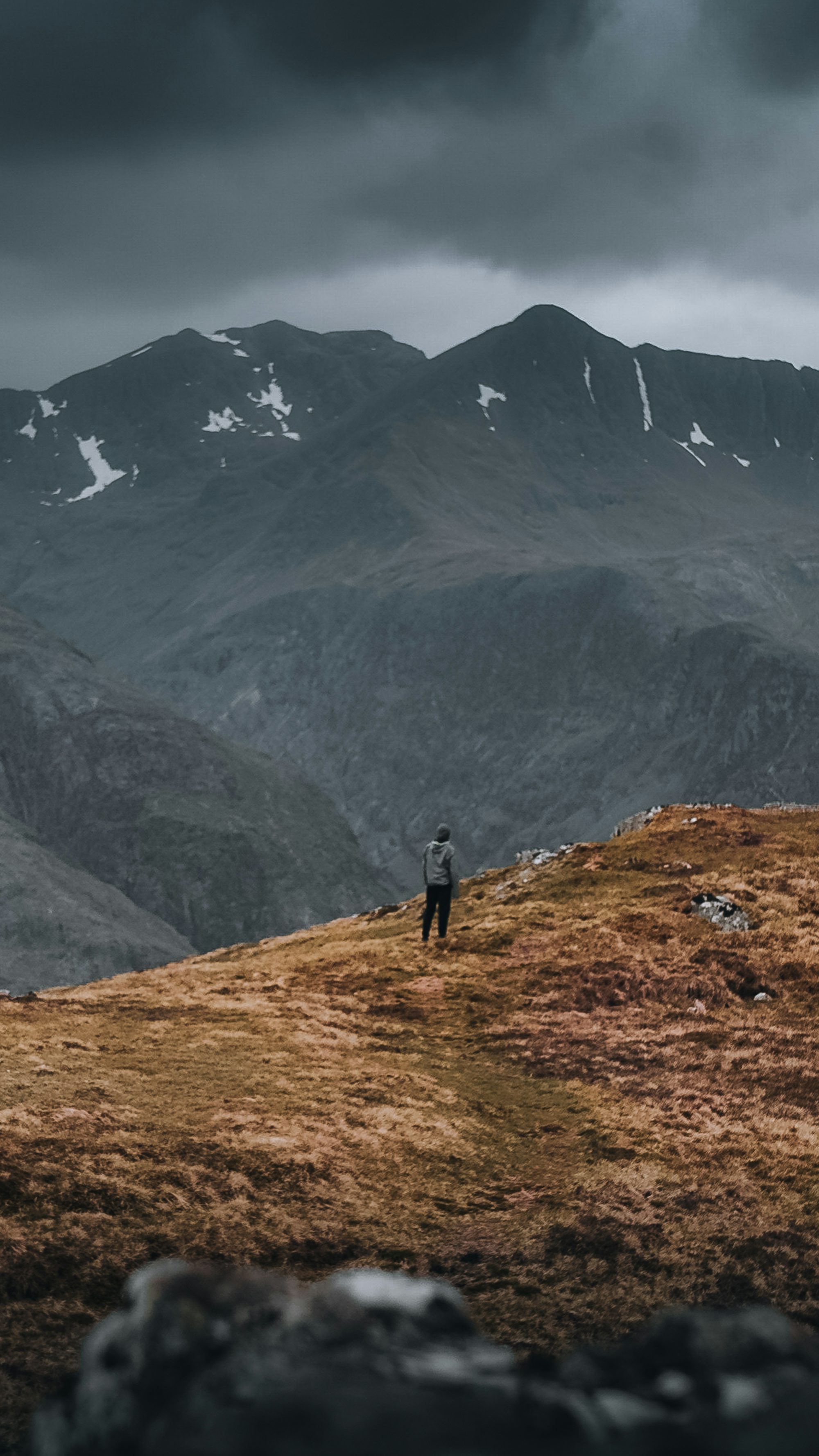 a man standing on top of a grass covered hillside